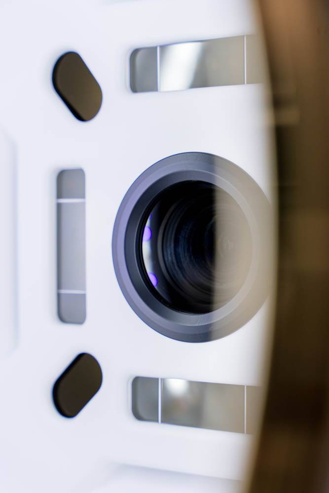 Zbliżenie obiektywu aparatu otoczonego białą, prostokątną ramą o geometrycznych kształtach i odbiciach - artystyczne ujęcie inspirowane medycyną estetyczną Wrocławia.