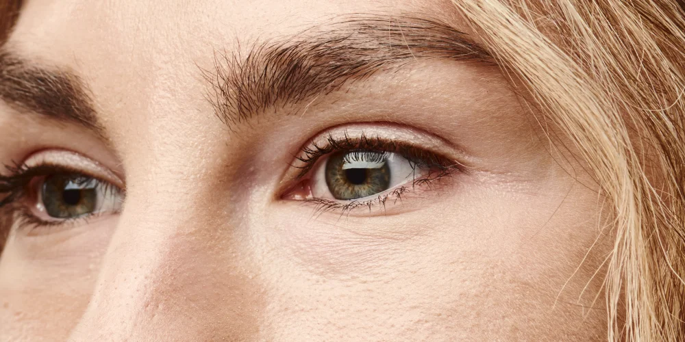 Close-up of a person's face focused on their light-colored eyes, eyebrows, and part of their nose and forehead, with light skin and blond hair visible—an effect often sought at a klinika medycyny estetycznej.