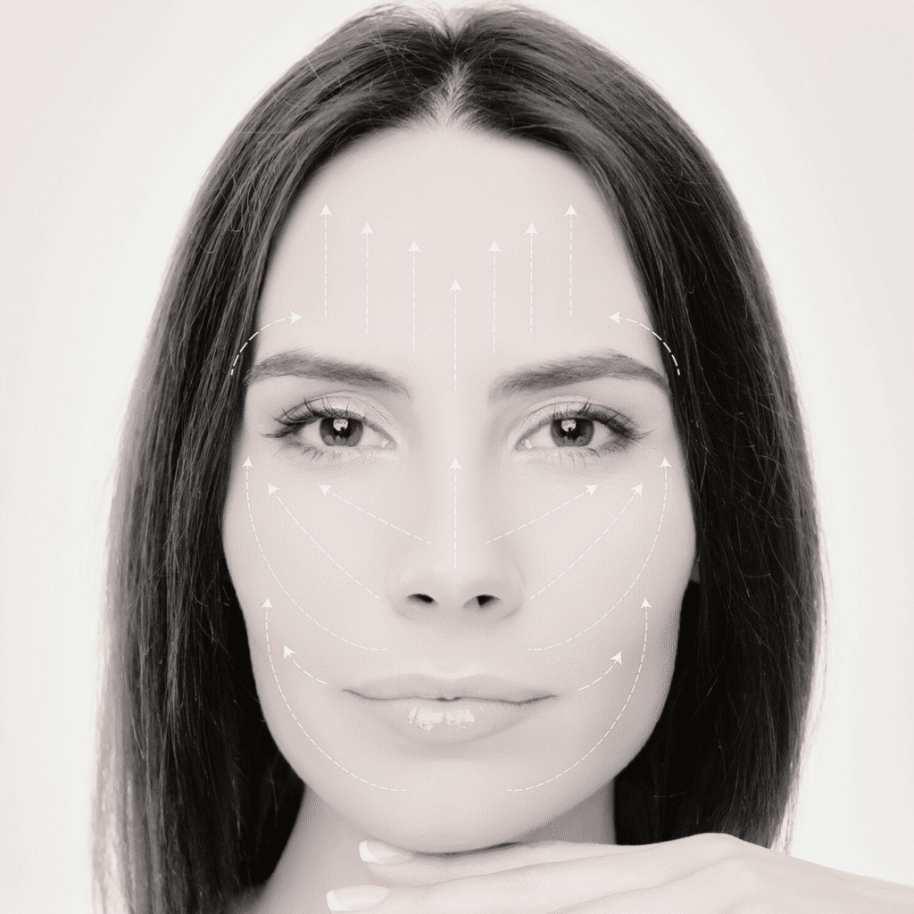 A woman with straight dark hair rests her chin on her hand. White arrows on her face illustrate facial lifting techniques, reflecting the expert care available at a klinika medycyny estetycznej specializing in medycyna estetyczna Wrocław.