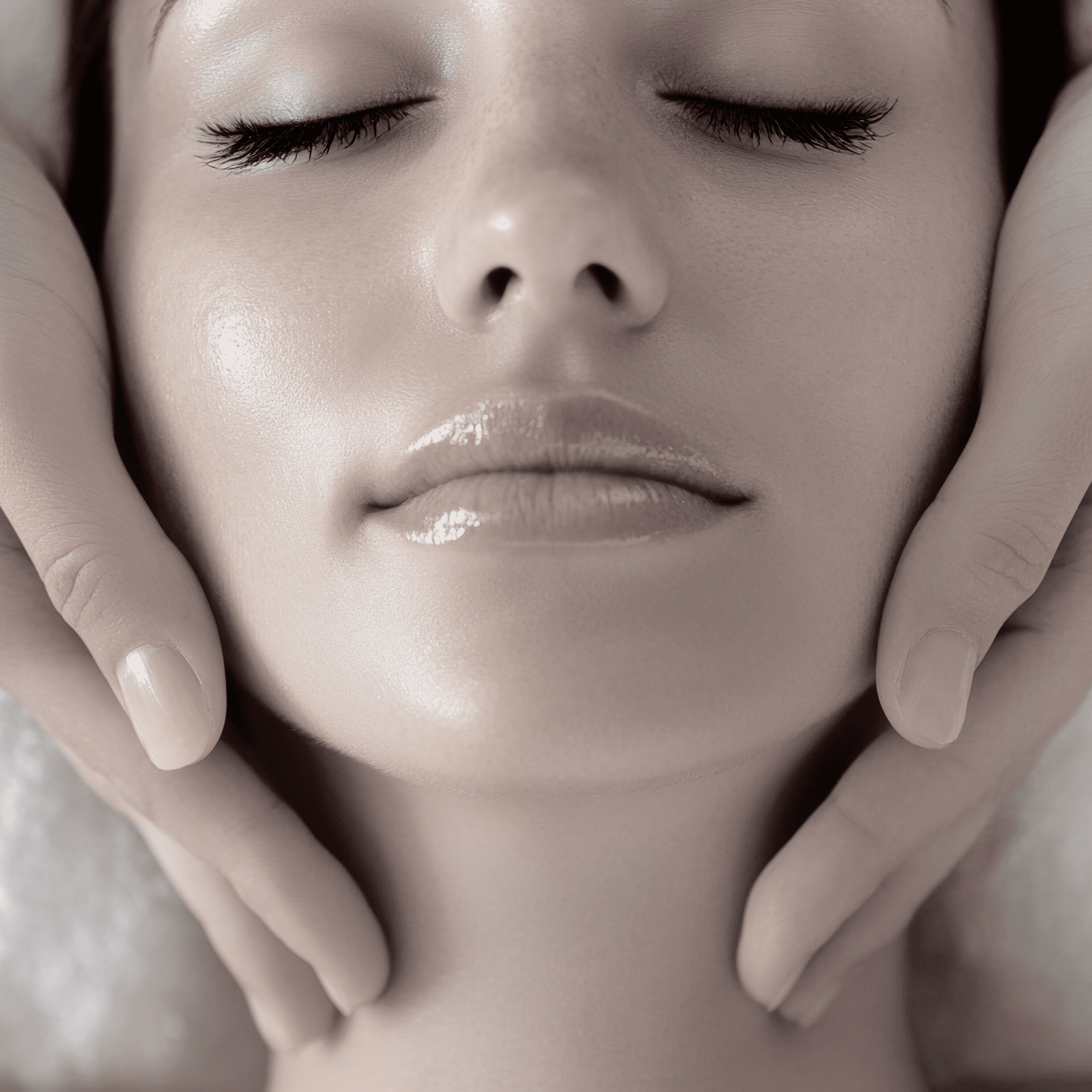 A close-up of a woman with smooth, glowing skin receiving a facial massage at a klinika medycyny estetycznej. Her eyes are closed, and hands gently cradle her face, creating a calm and relaxing atmosphere.